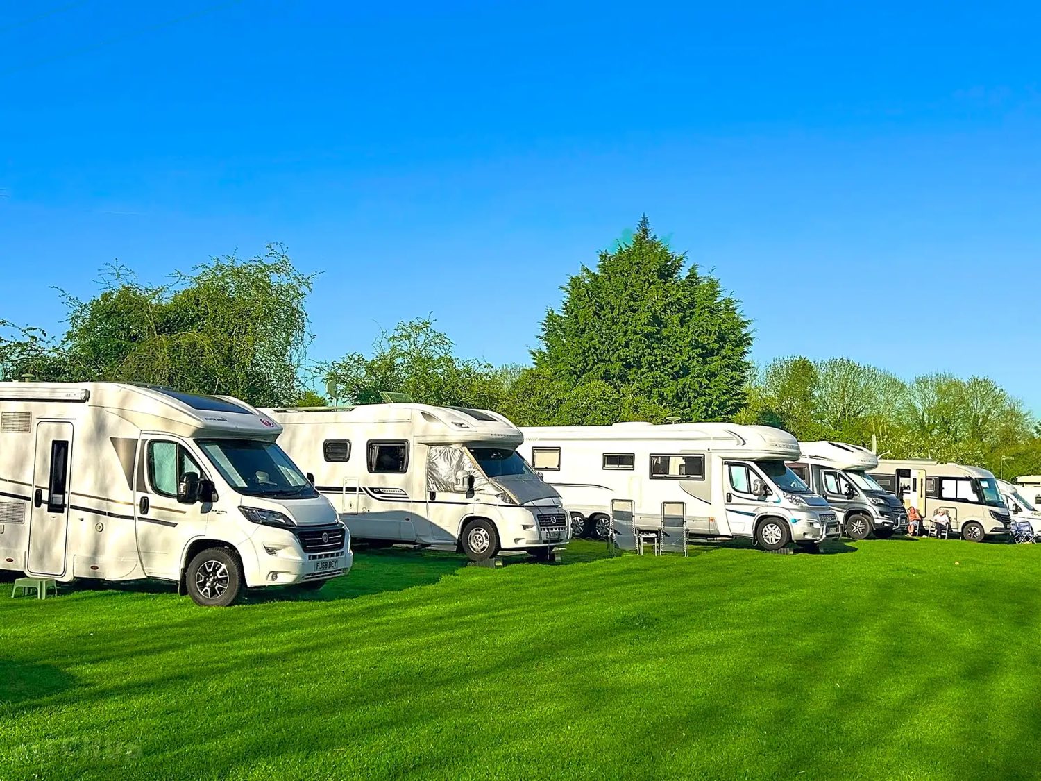 Motorhomes and campervans pitched on the grass at The Cottage of Content campsite.