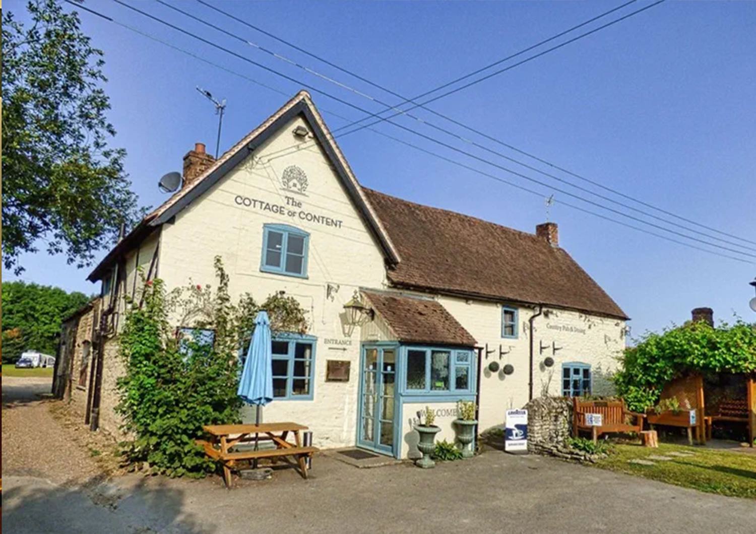 The Cottage of Content - a country pub with duck-egg blue windows and picnic benches out front.