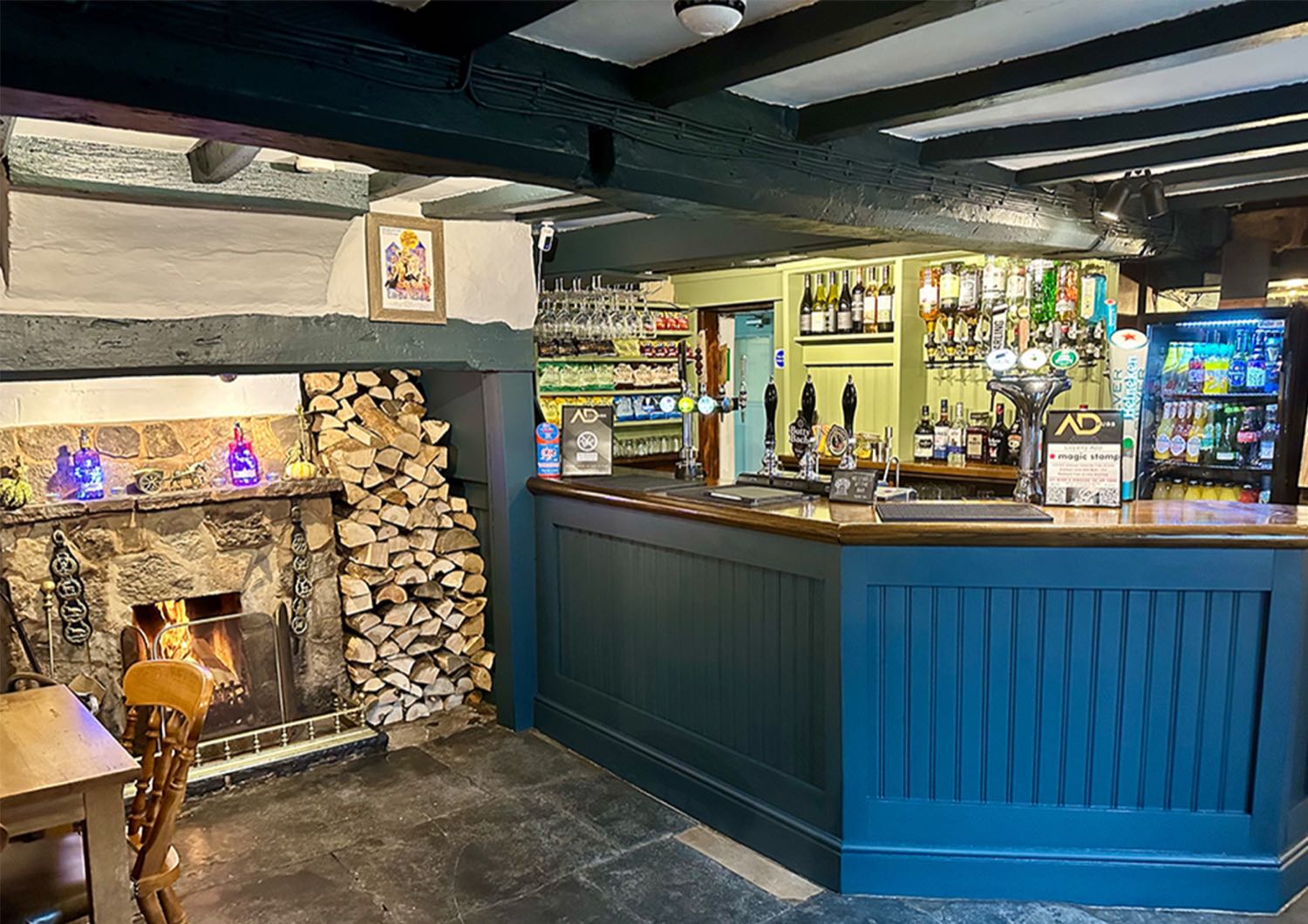 Inside The Cottage of Content - the bar with its beams, stools and a fire lit at the end of the room.